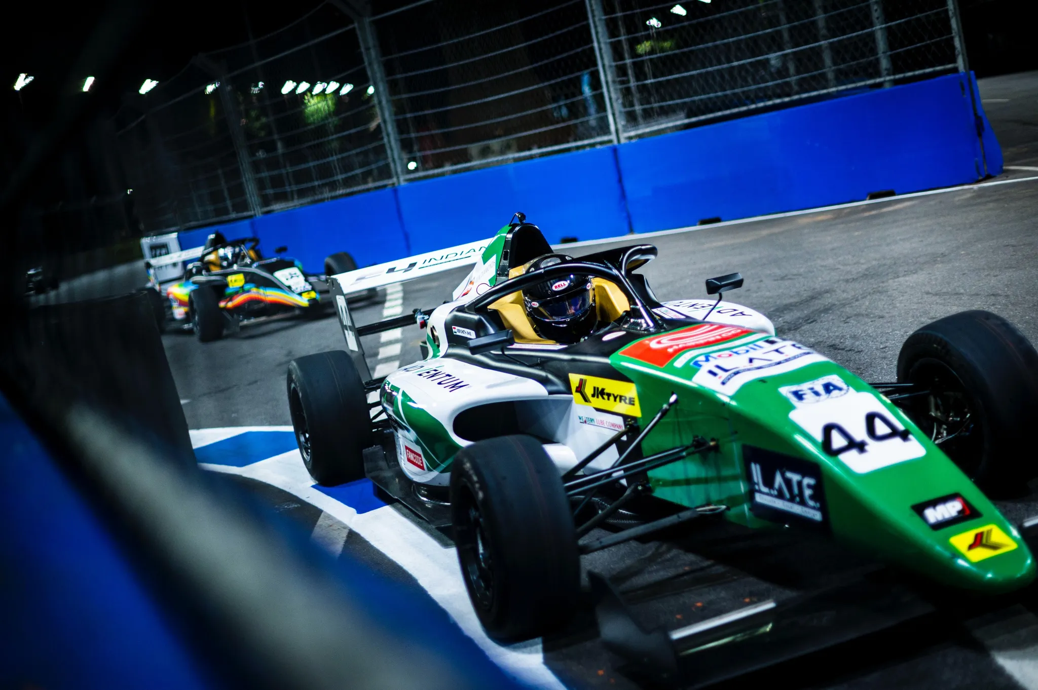 Formula 4 cars racing at night